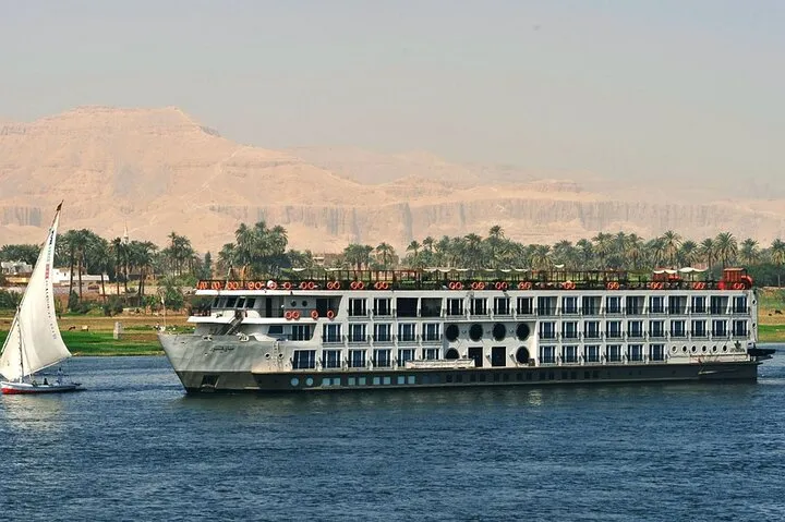 A 5-star Nile cruise ship passing a felucca below the Theban hills on a luxury Egypt tour, Luxor, Egypt