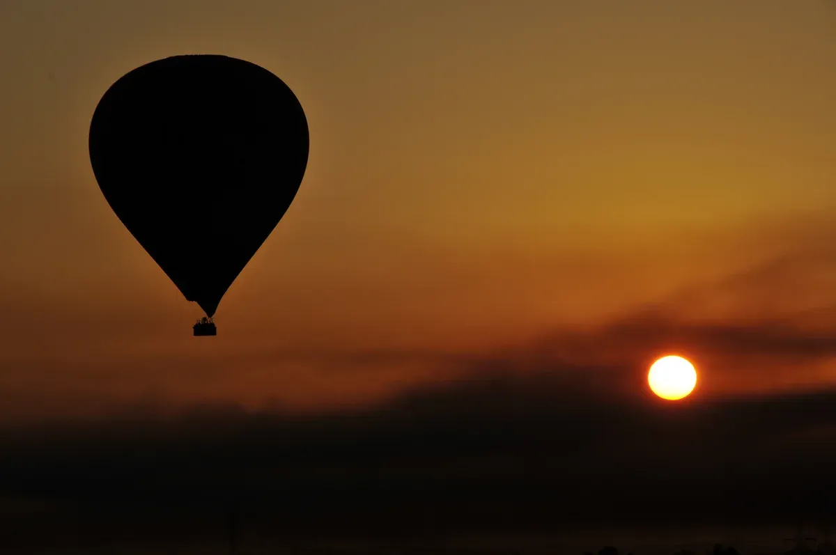 A hot air balloon silhouetted against the sunrise on a luxury Egypt tour, Luxor, Egypt